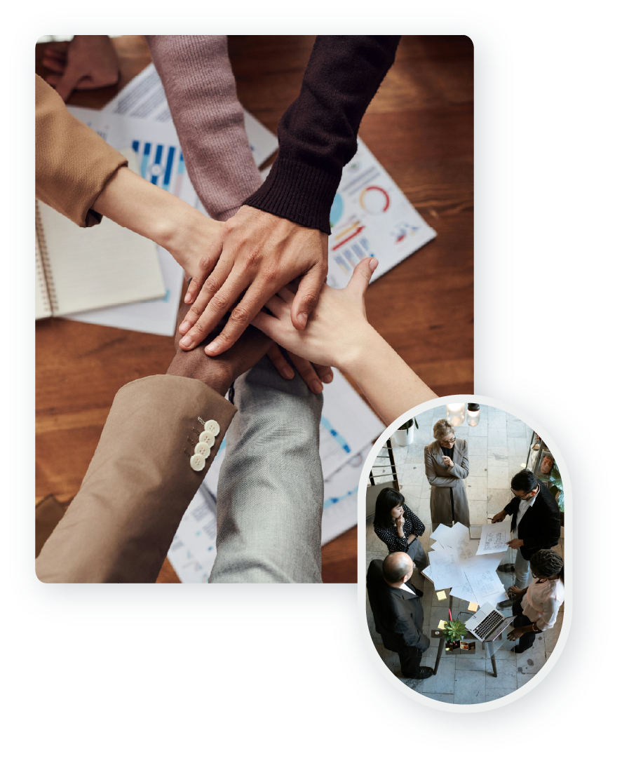 Hands stack on top of each other in a show of teamwork and a group of people collaborating over a desk full of project documents. 