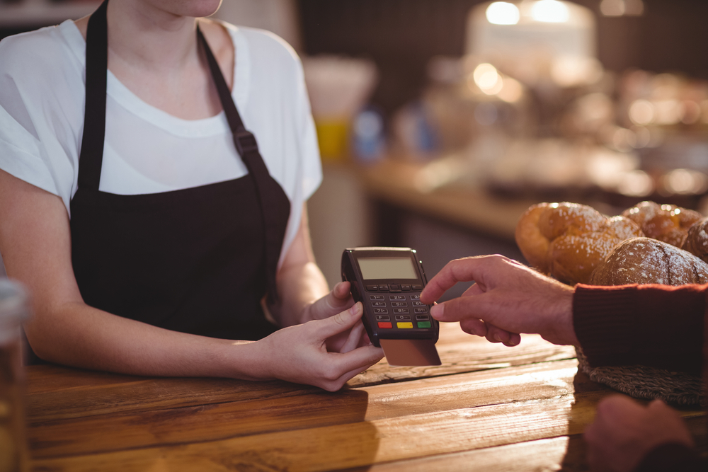 Barista accepting customer tips — illustrating IRS & DOL tip pooling rules for service industry employers.
